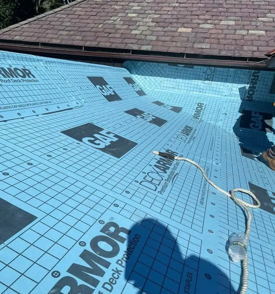 Synthetic roof underlayment covering a low slope roof section next to a slate roof