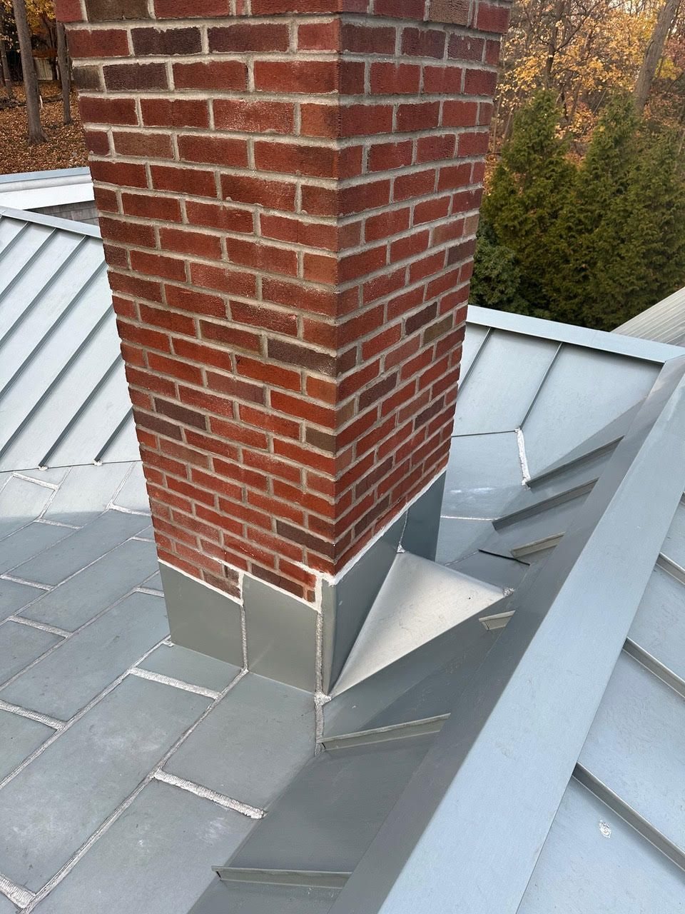 Brick chimney on metal roof with slate detail